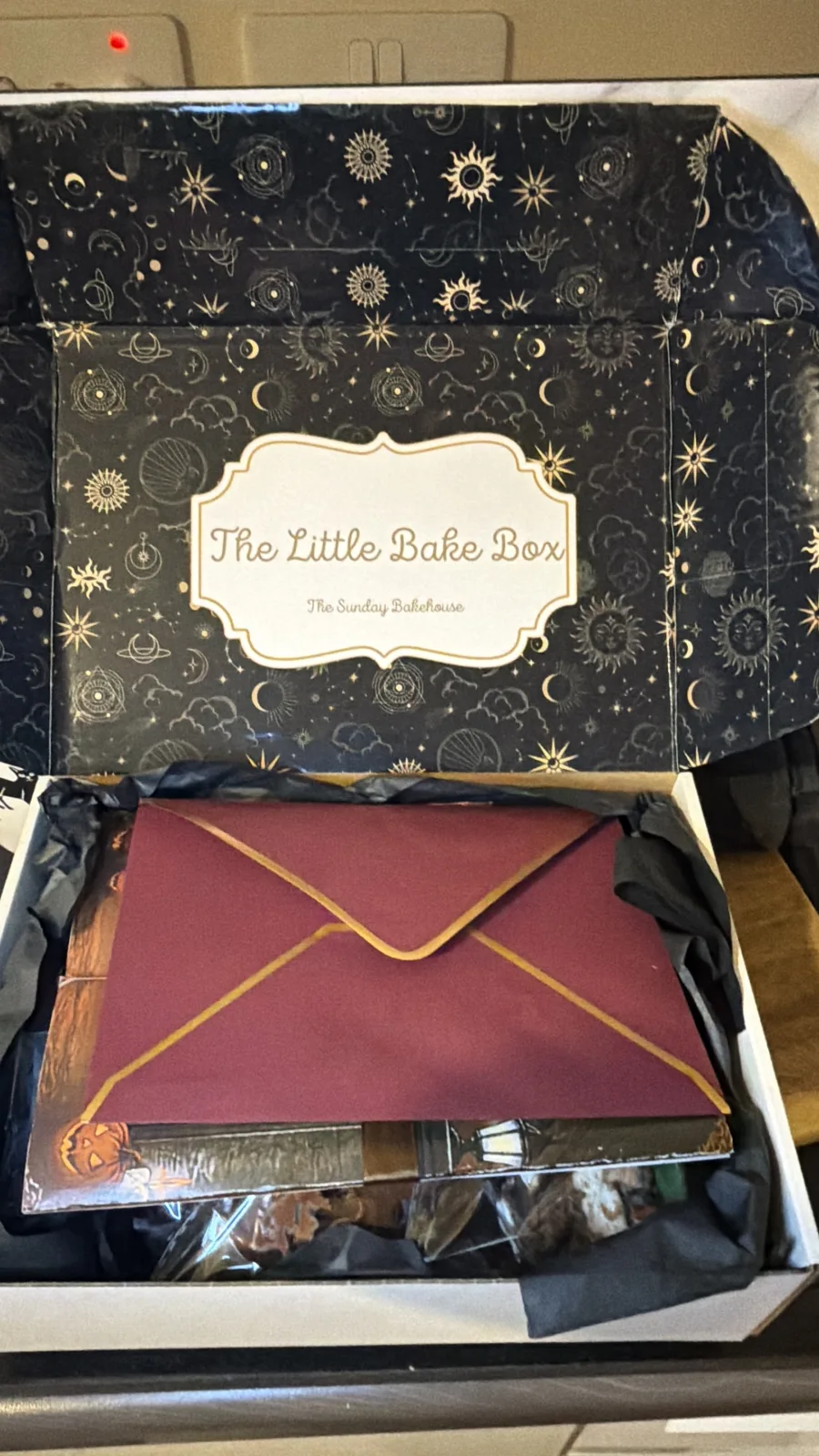 An open Little Bake Box with wrapped bakes and a purple envelope